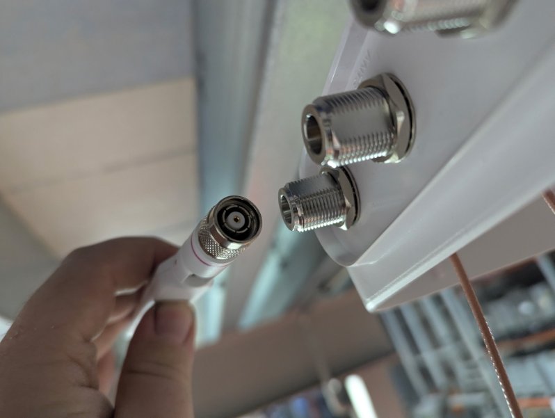 Cisco RP-TNC antenna connector held against an incompatible N-type male bulkhead port on a NEMA enclosure