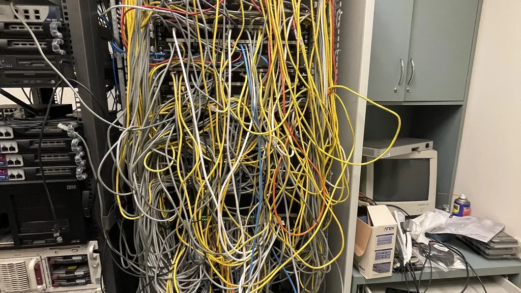 Comms room cabinet with a dense tangle of unlabelled patch leads and a few green switch lights showing which links are live.