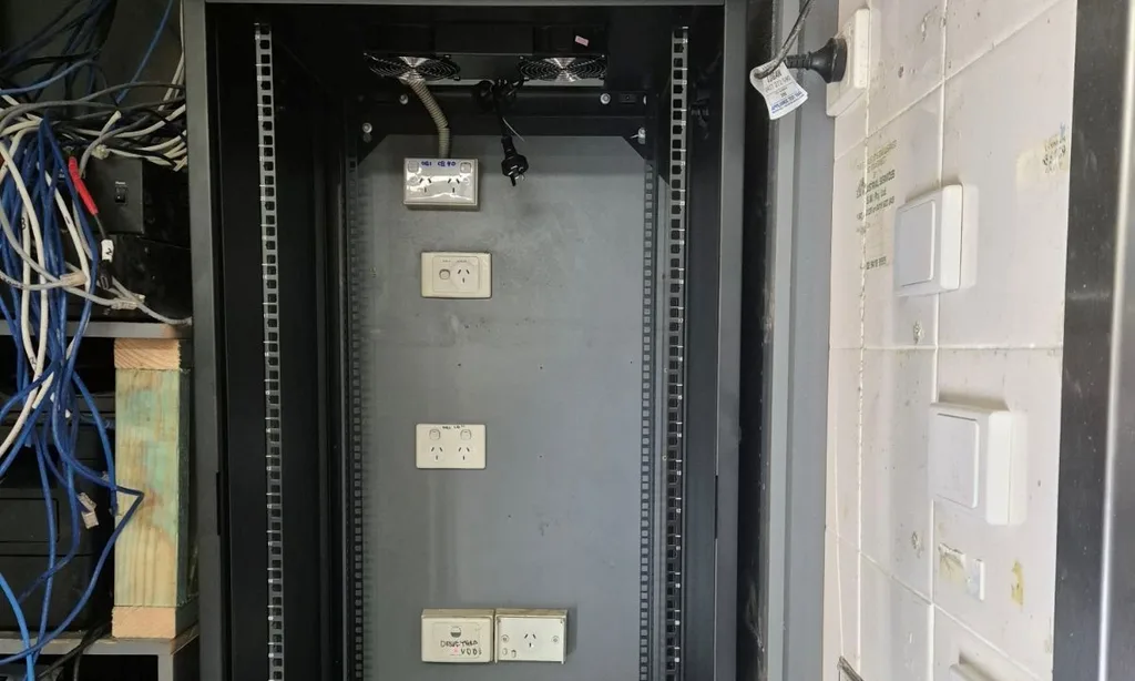 New data cabinet on a remediation job. The power outlets on its back panel were kept from the old setup and still carry handwritten felt-pen labels from an earlier installer.