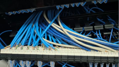 Unsupported cable bundle terminated into the back of a punch-down patch panel, with no strain relief bar fitted