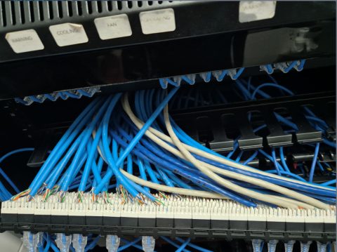 Unsupported cable bundle terminated into the back of a punch-down patch panel, with no strain relief bar fitted