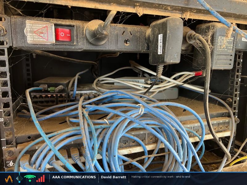Congested network rack with cable bundle obstructing switch airflow, covered in dust and cobwebs