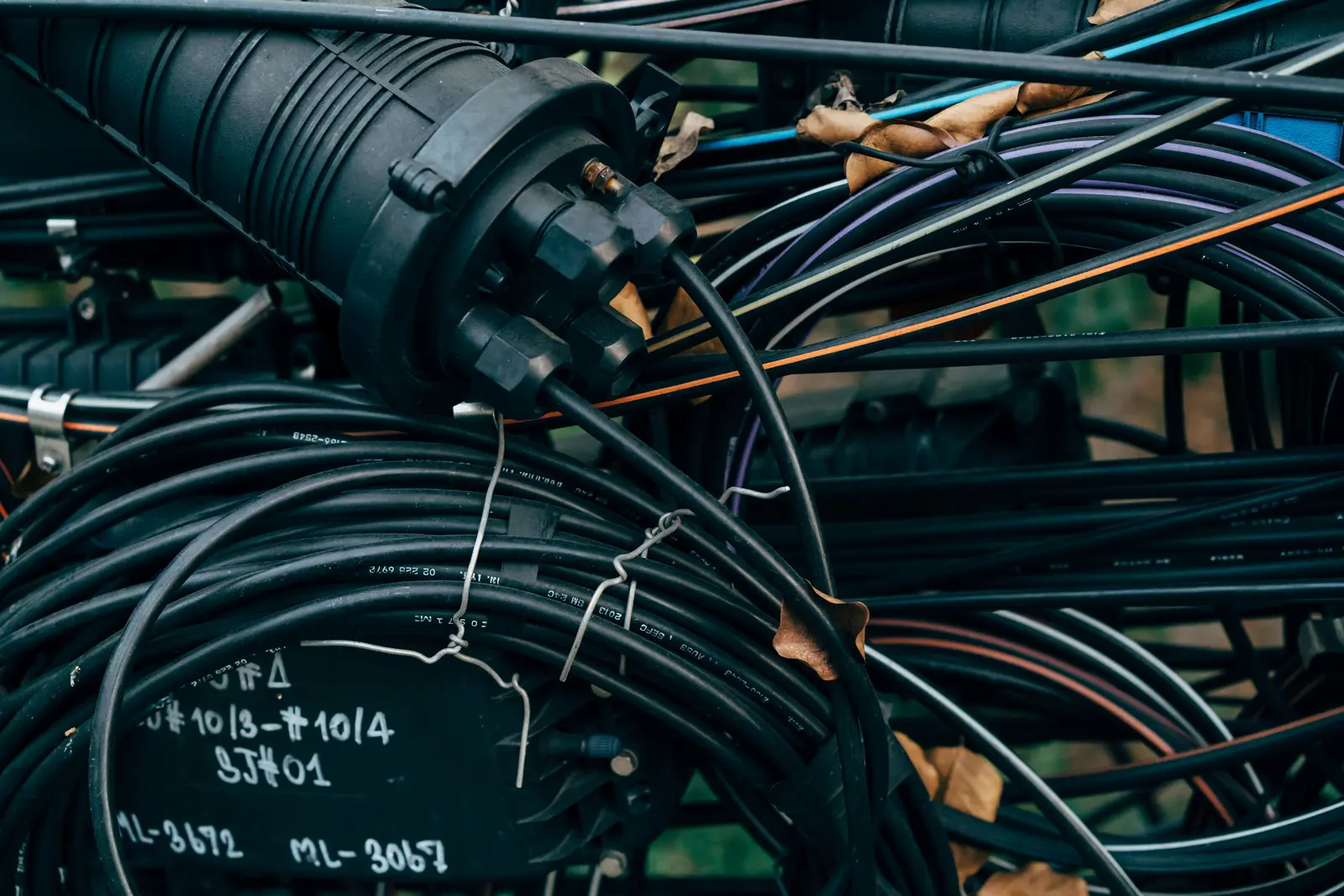 Exposed fibre conduit coiled on a footpath — the physical layer that redundant network diagrams depend on.