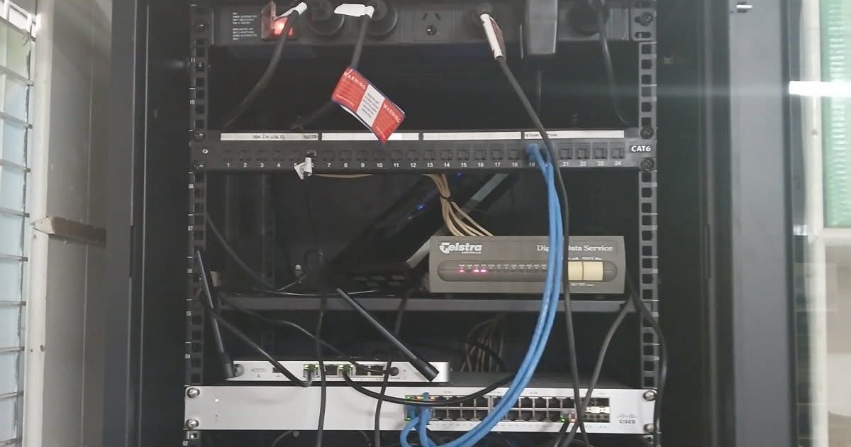 Undocumented network cabinet with carrier NTU, switch and tangled patch leads
