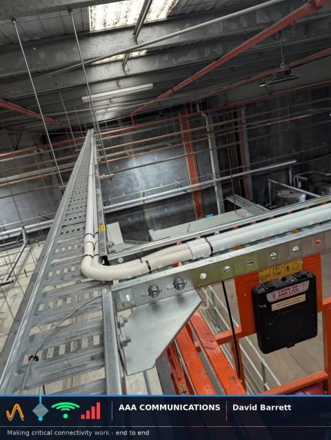 Warehouse cable tray carrying fibre backbone at height with flex transition around structural obstruction